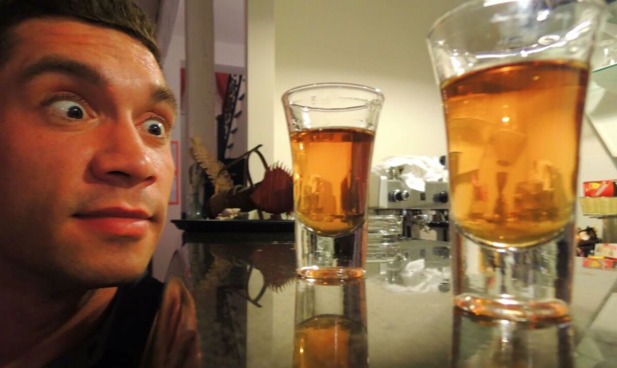 a man looking at two glasses of supreme rakija